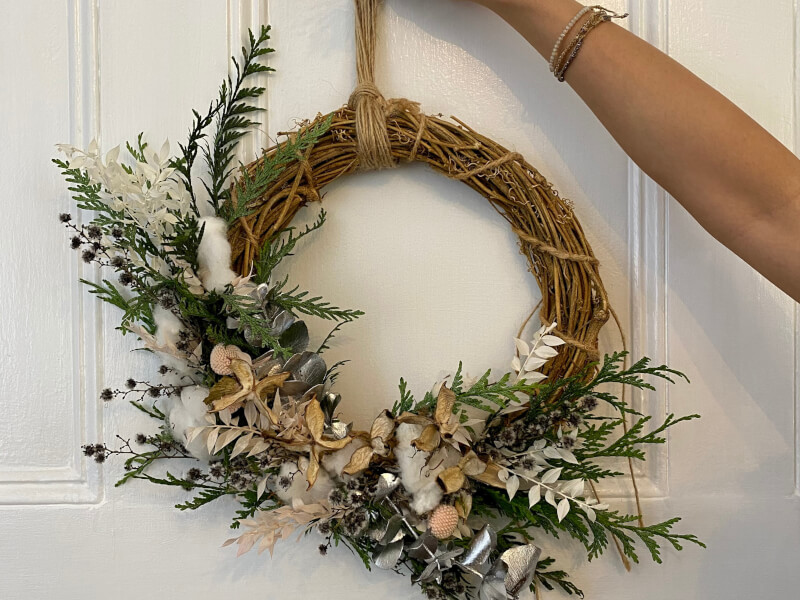 holding up a Christmas wreath